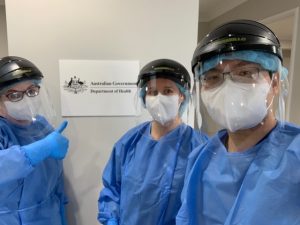 Three health care workers stand in personal protective equipment