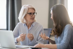 Old woman consulting with person at desk