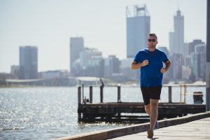 A front-view shot of a caucasian mid-adult man jogging on a hot summer's day in Perth, Australia.